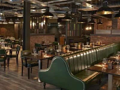 a restaurant with wooden tables and green chairs at Village Hotel Glasgow in Glasgow