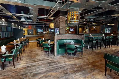 a restaurant with wooden tables and green chairs at Village Hotel Glasgow in Glasgow