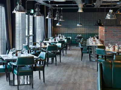 a dining room with tables and green chairs at Village Hotel Glasgow in Glasgow