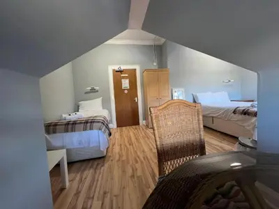 a room with two beds and a chair in it at Gothenburg Hotel in Rosyth