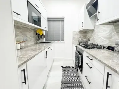 a white kitchen with white cabinets and a stove at Stylish Modern Glasgow Home with Excellent Value in Glasgow