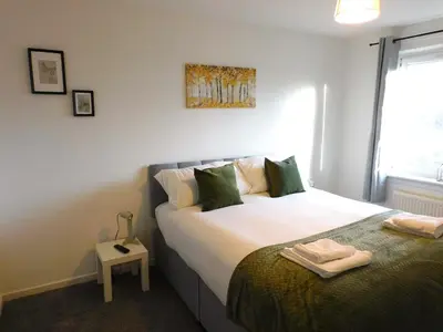 a bedroom with a large bed with green pillows at 4 Bedroom Newly Refurbished Home in East Kilbride in East Kilbride