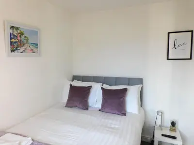 a bedroom with a white bed with purple pillows at 4 Bedroom Newly Refurbished Home in East Kilbride in East Kilbride