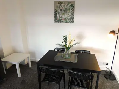 a table with chairs and a vase with flowers on it at 4 Bedroom Newly Refurbished Home in East Kilbride in East Kilbride