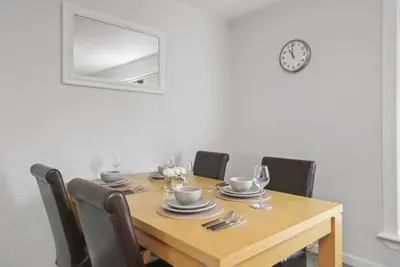 a dining room table with chairs and a clock on the wall at BridgeCity Hidden Gem in the heart of Falkirk Roughland house Stirlingshire in Carron