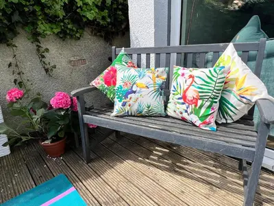 three pillows sitting on a bench on a patio at Kennedy Cottage by Troon beach in Troon