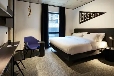a hotel room with a bed and a blue chair at The Social Hub Glasgow Extended Stay in Glasgow
