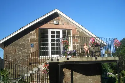 a building with a balcony with flowers on it at Loaninghead Holidays in Drymen