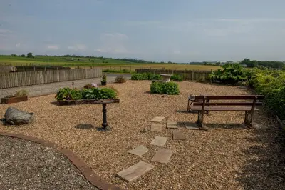 a park bench sitting in a garden with plants at Loaninghead Holidays in Drymen