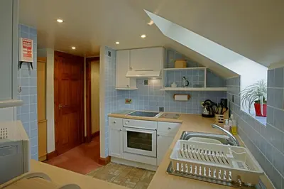 a kitchen with white cabinets and blue tiles at Loaninghead Holidays in Drymen