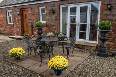a patio with chairs and a table with yellow flowers at Loaninghead Holidays in Drymen