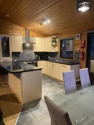 a kitchen with white cabinets and a table and chairs at Lomond Lodge Rowardennnan in Rowardennan