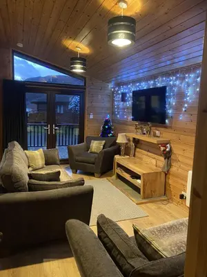 a living room with couches and a flat screen tv at Lomond Lodge Rowardennnan in Rowardennan