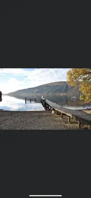 a dock on a lake with a hill in the background at Lomond Lodge Rowardennnan in Rowardennan