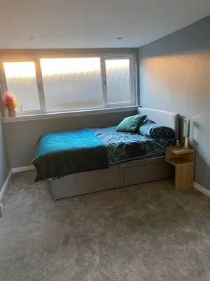 a bedroom with a bed and two windows at The Barn in Hawkhead