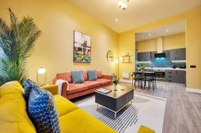 a living room with a yellow couch and a kitchen at Large Central Station 2 Bed Apartment A2 in Glasgow