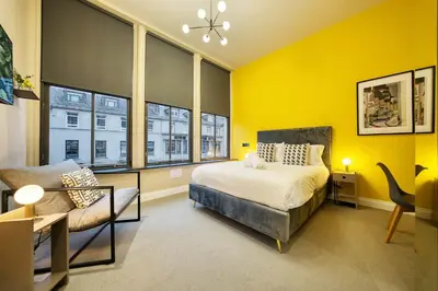 a bedroom with yellow walls and a bed and a chair at Large Central Station 2 Bed Apartment A2 in Glasgow