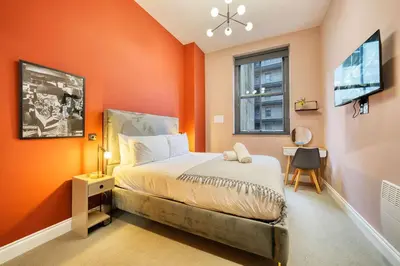a bedroom with orange walls and a bed and a window at Stunning Central Station 2 Bed Apartment B4 in Glasgow