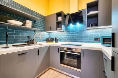 a kitchen with white counters and blue tiles at Stunning Central Station 2 Bed Apartment B4 in Glasgow