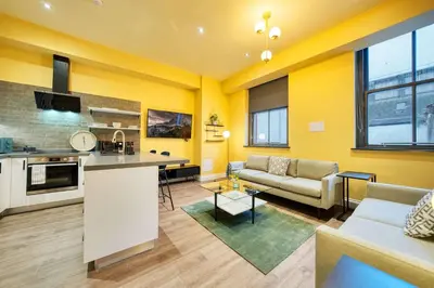a kitchen and a living room with yellow walls at Grand Central Station 1 Bed Apartment A5 in Glasgow
