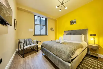 a yellow bedroom with a bed and a chair at Grand Central Station 1 Bed Apartment A5 in Glasgow