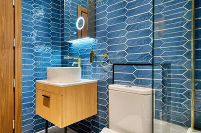 a blue tiled bathroom with a sink and a toilet at Lovely Central Station 1 Bed Apartment A6 in Glasgow