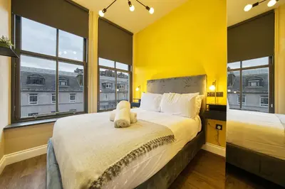 a yellow bedroom with a bed with a stuffed animal on it at Stunning Central Station 1 Bed Apartment A7 in Glasgow