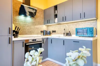a kitchen with blue cabinets and a tv on the wall at Cozy Central Station 1 Bed Apartment B8 in Glasgow
