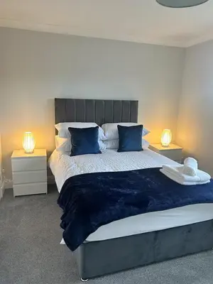 a bedroom with a large bed with blue pillows at Modern Staycation Apartment in Caldercruix