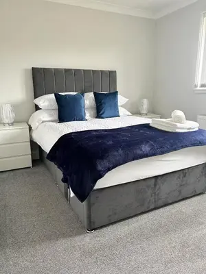 a bedroom with a large bed with blue pillows at Modern Staycation Apartment in Caldercruix