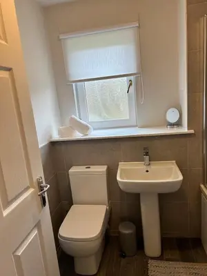 a bathroom with a toilet and a sink and a window at Modern Staycation Apartment in Caldercruix