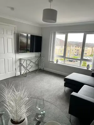 a living room with a couch and a table at Modern Staycation Apartment in Caldercruix