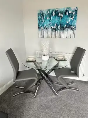 a glass table and chairs in a room with a painting at Modern Staycation Apartment in Caldercruix