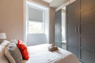 a bedroom with a bed with red pillows and a window at Spacious 3 bed home in Marchmont in Edinburgh
