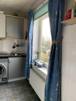 a kitchen with blue curtains in front of a window at Little Universe in Edinburgh