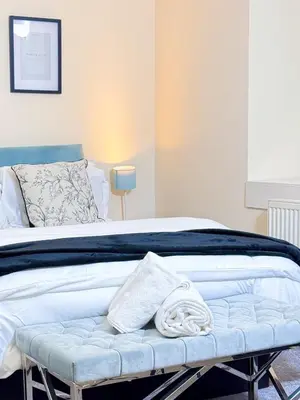 a bed with a bench with a towel on it at Glasgow City Centre Stylish Flat in Glasgow