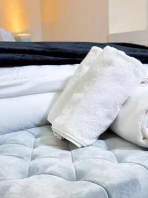 a bed with white sheets and towels on it at Glasgow City Centre Stylish Flat in Glasgow