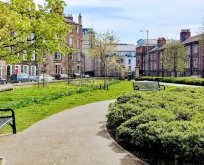 a park with two park benches and buildings at The Gardners apartment in City centre with parking in Edinburgh
