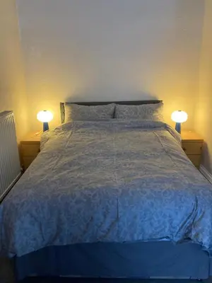 a bedroom with a bed with two lamps on two tables at Gilmore Flat in Edinburgh