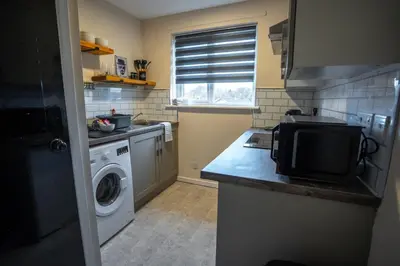 a kitchen with a washing machine and a microwave at 1 BDR Apartment At Caledonia Luxe Stays Short Lets & Serviced Accommodation Airdrie in Airdrie