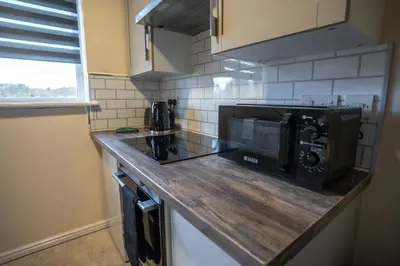 a kitchen with a counter top with a microwave at 1 BDR Apartment At Caledonia Luxe Stays Short Lets & Serviced Accommodation Airdrie in Airdrie