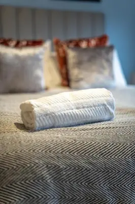 a white rolled up towel on top of a bed at Skye House in Grangemouth
