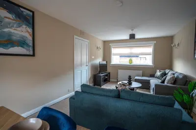 a living room with a blue couch and a table at Skye House in Grangemouth