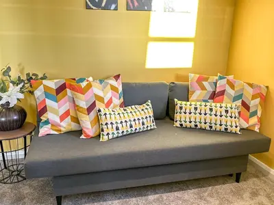 a couch with colorful pillows on it in a room at Sunny day new flat with 5 beds in Clydebank