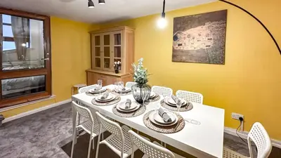 a dining room with a white table and white chairs at Sunny day new flat with 5 beds in Clydebank