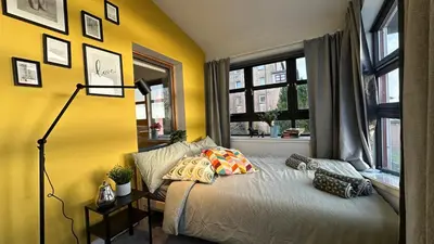 a bedroom with yellow walls and a bed with pillows at Sunny day new flat with 5 beds in Clydebank