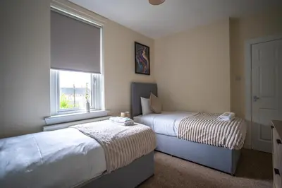 a bedroom with two beds and a window at Caledonia Apartment in South Cobbinshaw
