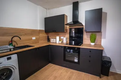 a kitchen with black cabinets and a sink and a washer at Caledonia Apartment in South Cobbinshaw