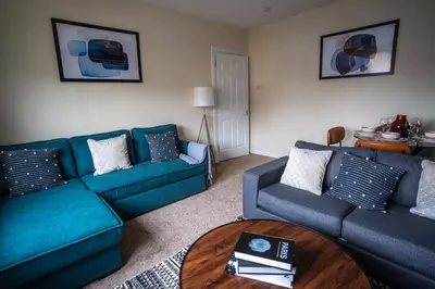 a living room with two blue couches and a table at Caledonia Apartment in South Cobbinshaw