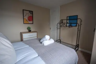 a bedroom with a white bed with a metal rack at Castlefern House in Rutherglen